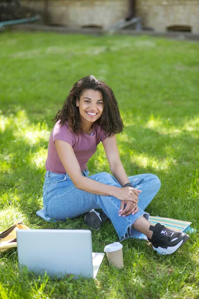 草の上に座って勉強している暗い肌の女性 — ストック写真