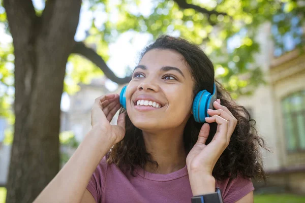 Sorrindo menina sonhadora em fones de ouvido ouvindo música — Fotografia de Stock