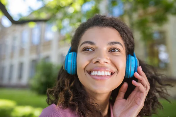 Sonriente joven soñadora en auriculares escuchando música — Foto de Stock