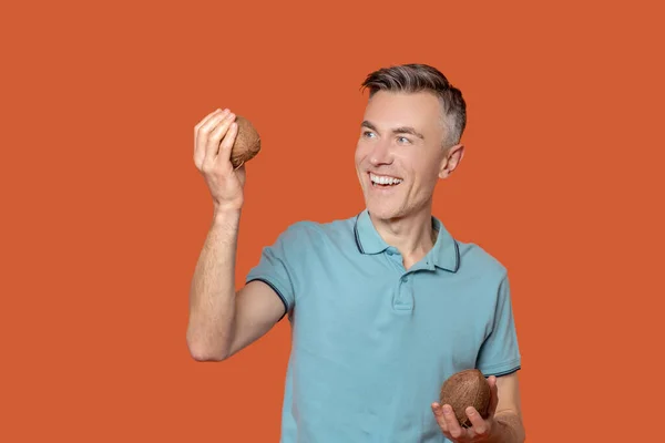 Glädjande man med kokosnötter i händerna — Stockfoto