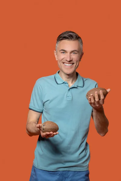 Man die kleine kokosnoten in zijn handpalmen houdt — Stockfoto