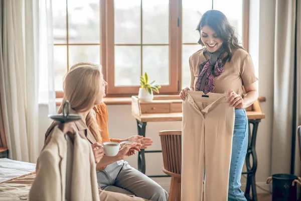 Dark-haired woman showing her new buyings to her friends — Stock Photo, Image