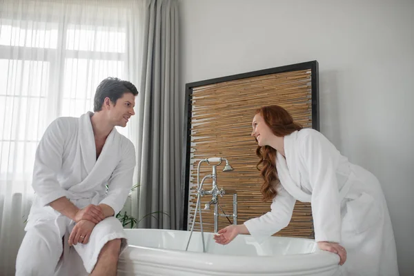 Una pareja de albornoces blancos preparando un baño —  Fotos de Stock