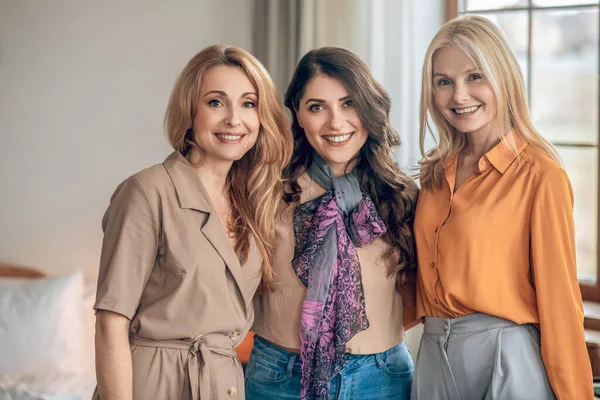 Tres mujeres en trajes elegantes sonriendo y luciendo felices — Foto de Stock