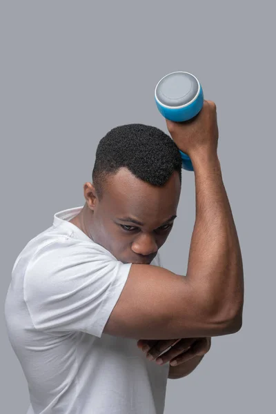 Un joven de piel oscura haciendo ejercicio con pesas — Foto de Stock