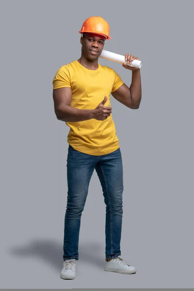 A dark-skinned construction engineer in a protective hemlet looking confident — Stock Photo, Image