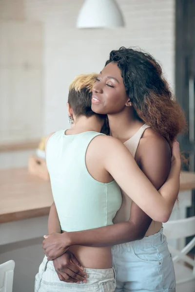 Two young female friends standing hugging at home — Stock Photo, Image