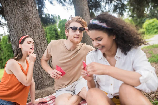 Tre vänner som har roligt att spela kort utomhus — Stockfoto