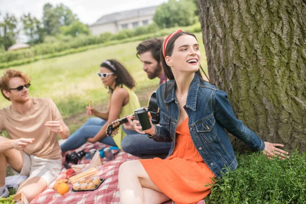 Menina feliz com bebida e amigos no piquenique — Fotografia de Stock