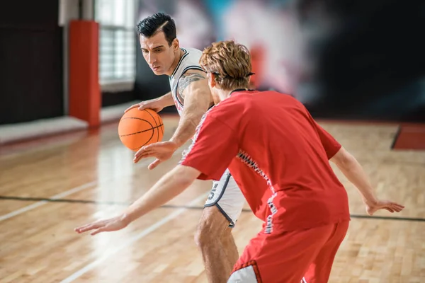 Two young men playing basketball and looking involved — Foto de Stock