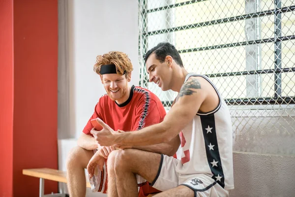 두 명의 농구 선수 가변화하는 방에 앉아 이야기하는 모습 — 스톡 사진