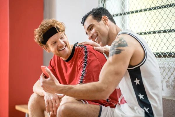 Twee basketbalspelers zitten in een kleedkamer en praten. — Stockfoto