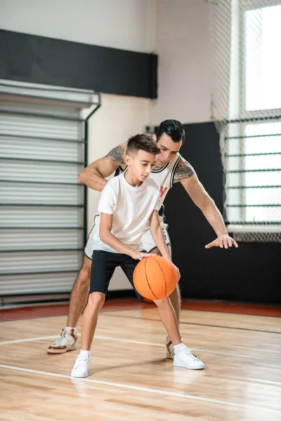 Dark-haired man training a teen in the gym — Stockfoto
