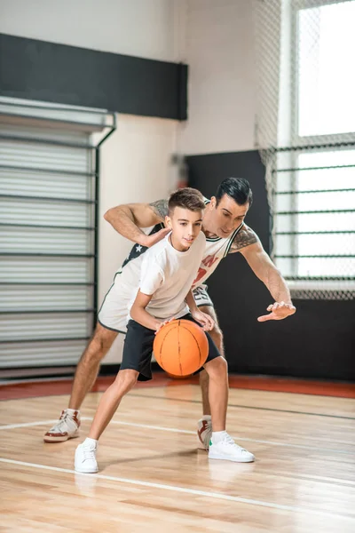 Hombre moreno jugando baloncesto con un chico — Foto de Stock