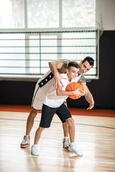 Homme aux cheveux bruns jouant au basket avec un garçon — Photo