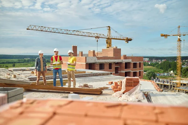 Byggherrar som konverserar med en ingenjör på byggarbetsplatsen — Stockfoto