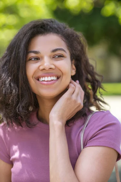 Lachende schattige mulatta in jeans en roze tshirt in het park — Stockfoto