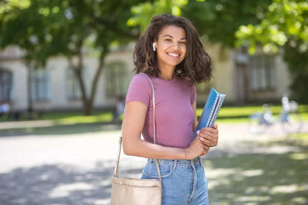 A girl in a pink tshirt holding textbooks in her hands — Stock Photo, Image