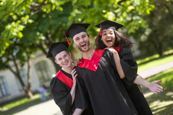 Grupo de graduados de pé no parque e se sentindo incrível — Fotografia de Stock