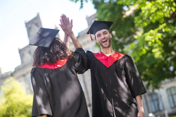 Двоє випускників почуваються схвильованими після закінчення навчання і виглядають щасливими — стокове фото