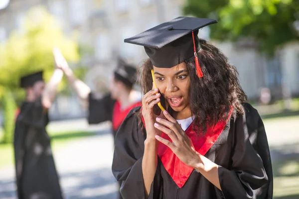 Een schattig meisje in academische jurk praten aan de telefoon — Stockfoto