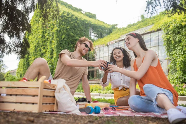 Guy en twee meisjes strekken hand uit met drank — Stockfoto