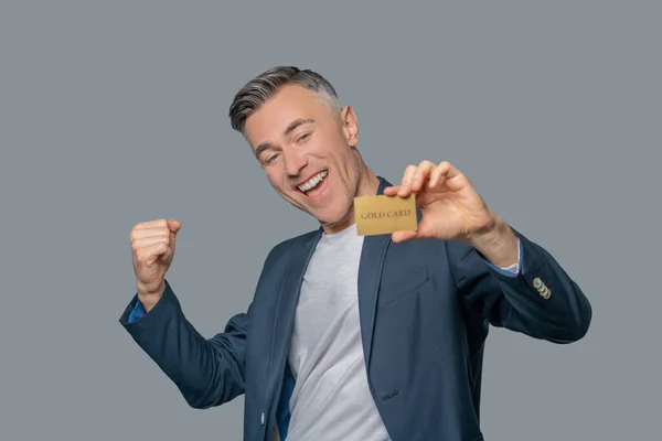 Homme enthousiaste avec carte bancaire en or — Photo