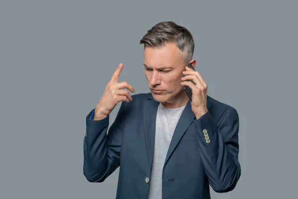 Serious gesturing man talking on smartphone — Stock Photo, Image