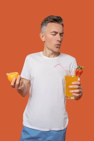 Serieuze man met cocktail en citrus in handen — Stockfoto