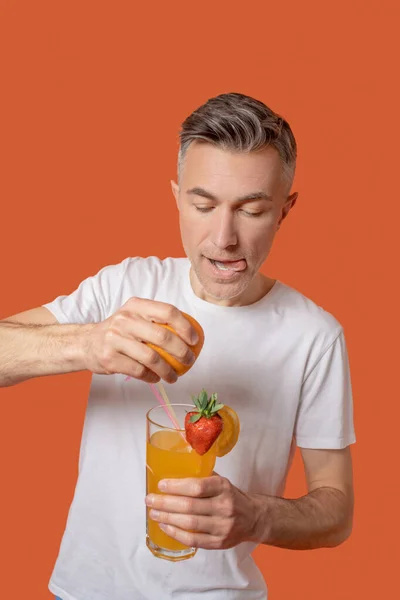 Aufmerksamer Mann drückt Orangensaft ins Glas — Stockfoto