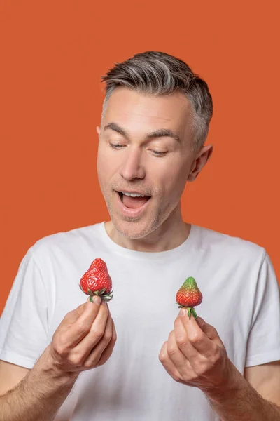 Fröhlicher Mann mit Erdbeere in der Hand — Stockfoto