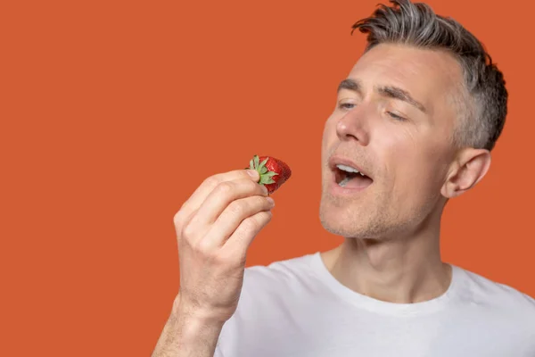 Man met aardbeien in de buurt van open mond — Stockfoto