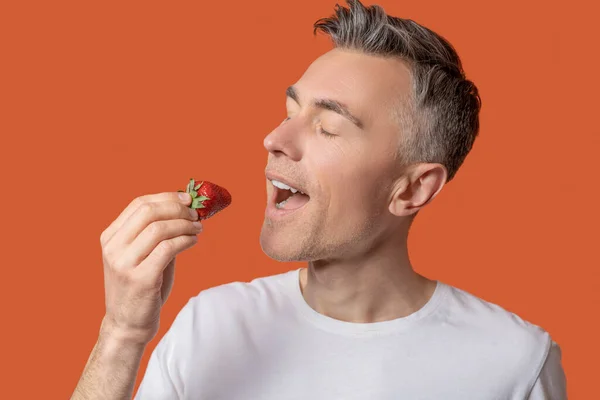 Man with closed eyes open mouth and with strawberries — Stock Photo, Image