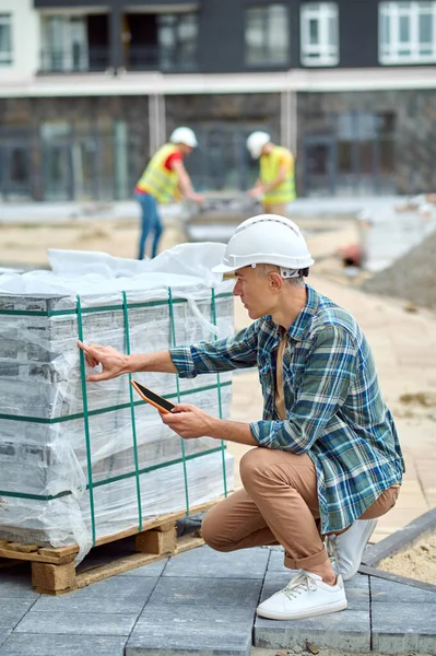 Ingeniero en un casco protector que inspecciona los materiales de construcción fuera —  Fotos de Stock