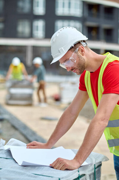 Concentrated worker in a hardhat examining a new building plan