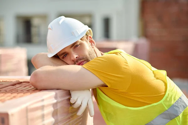 Sad tired builder in a protective helmet resting after hard work — Stock Photo, Image