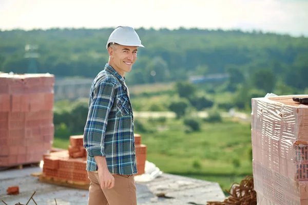 Trabajador de mediana edad de alto espíritu de pie entre los materiales de construcción —  Fotos de Stock