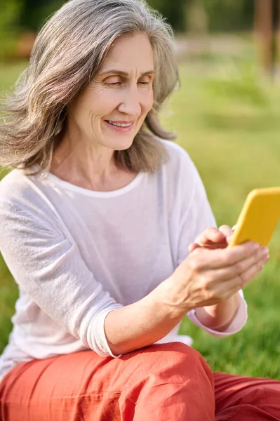 Mujer adulta en ropa casual con teléfono inteligente al aire libre — Foto de Stock
