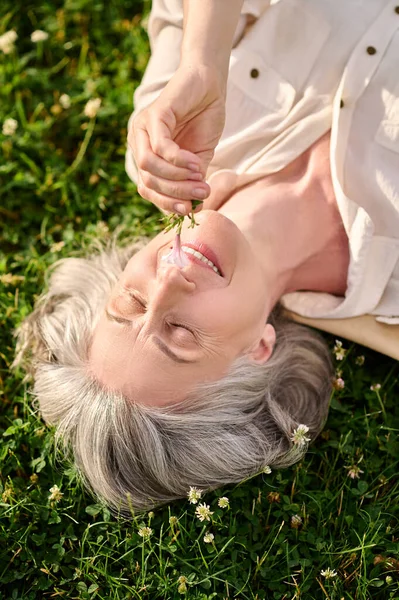 Mujer con flor en la mano acostada en el césped —  Fotos de Stock