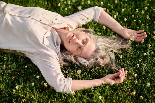 Удовольственная женщина дремлет на цветущей лужайке — стоковое фото
