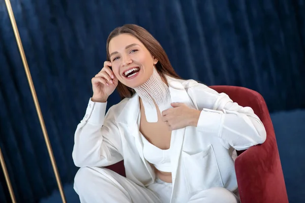 Молода жінка зі стрічками на шиї сидить на стільці і виглядає весело — стокове фото