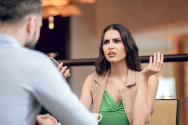 Genç bir kadın bir erkekle konuşuyor ve hayal kırıklığına uğramış görünüyor.