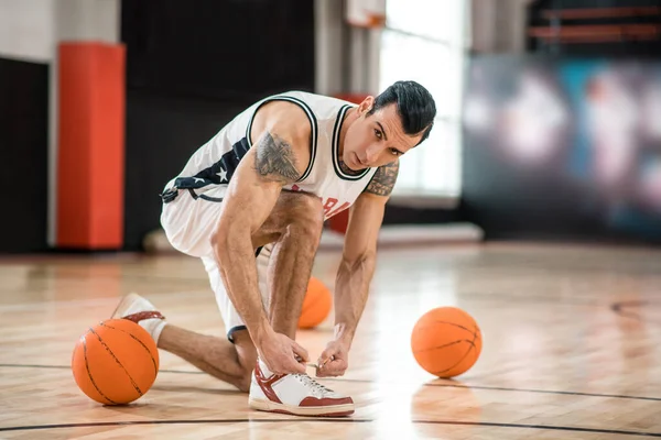 Junger Mann mit Tätowierung trainiert im Fitnessstudio und wirkt konzentriert — Stockfoto