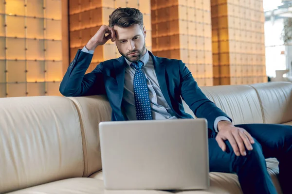 Homme barbu dans un costume travaillant sur un ordinateur portable et regardant concentré — Photo