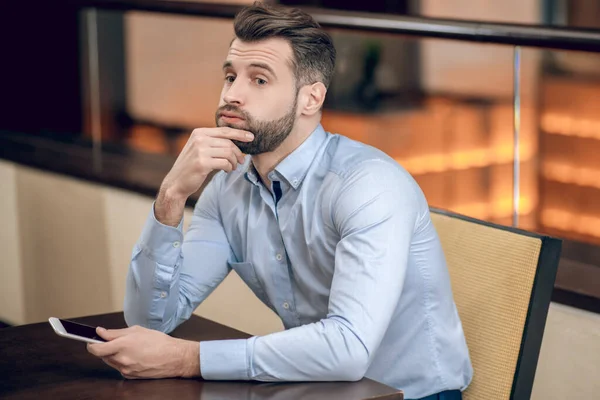 Ung skäggig man sitter vid bordet och väntar — Stockfoto