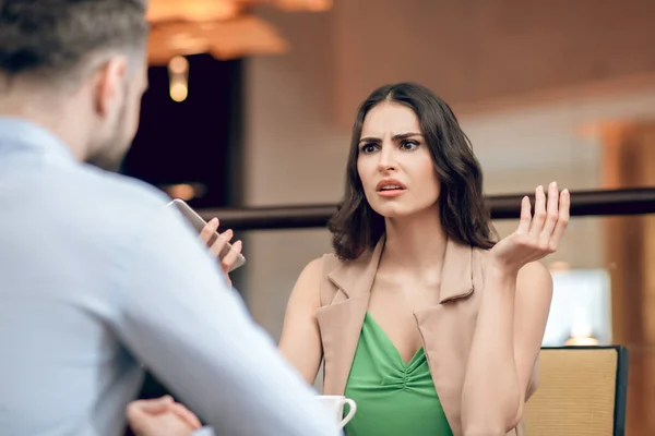 Jonge vrouw praat met een man en kijkt teleurgesteld — Stockfoto
