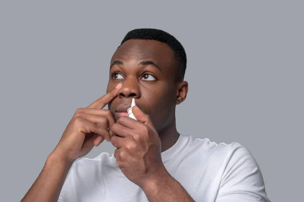 Un hombre de piel oscura cayendo gotas en la nariz — Foto de Stock