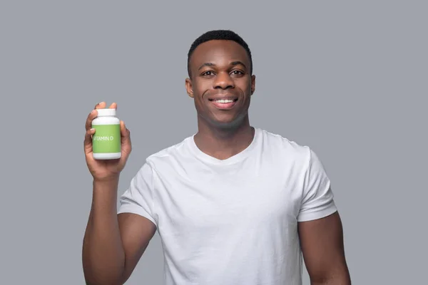 Un hombre de piel oscura en un thsirt blanco eligiendo vitaminas — Foto de Stock