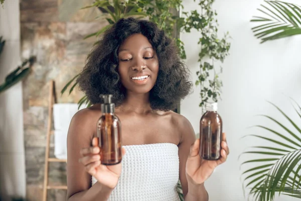Afroamerikanerin mit nackten Schultern mit Kosmetikprodukt — Stockfoto
