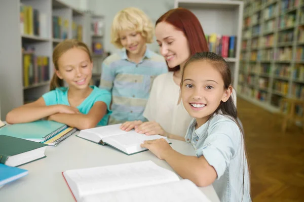 Fröhliche Schülerin posiert während einer Lesestunde für die Kamera — Stockfoto